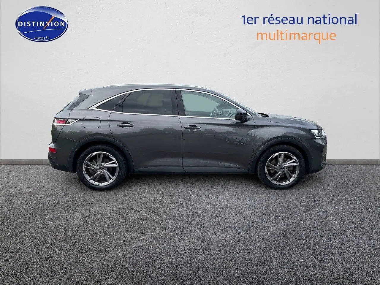 Vue latérale droite du DS7 Crossback gris platinium métallisé, SUV hybride rechargeable élégant stationné sur sol gris.