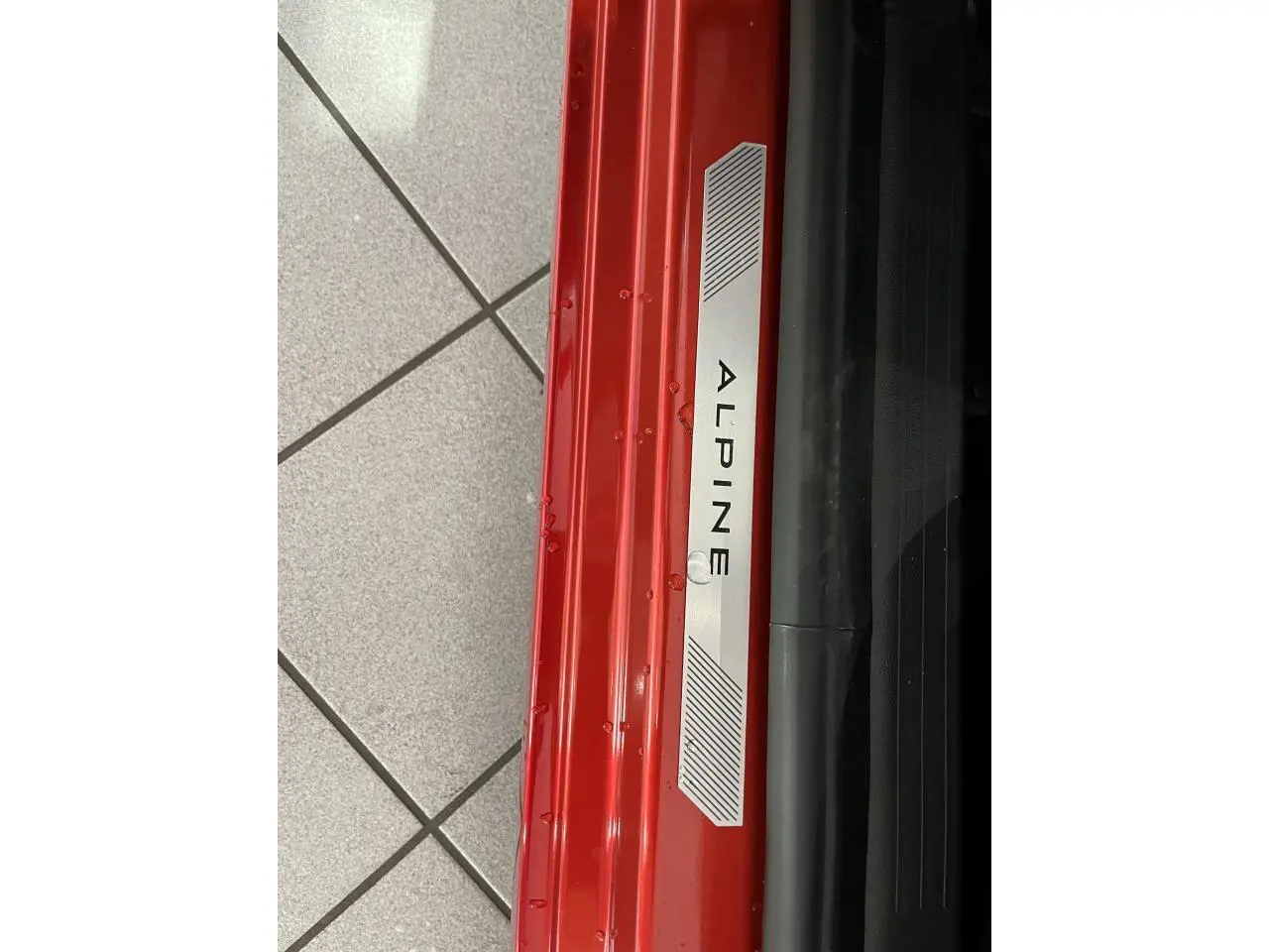 Gros plan sur la plaque de seuil de porte rouge de la Renault Clio 2024 version Esprit Alpine avec logo Alpine.