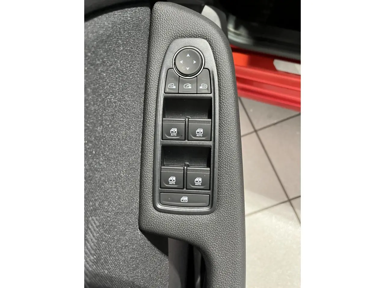 Commande des vitres électriques et réglage des rétroviseurs sur la porte côté gauche d'une Renault Clio rouge 2024