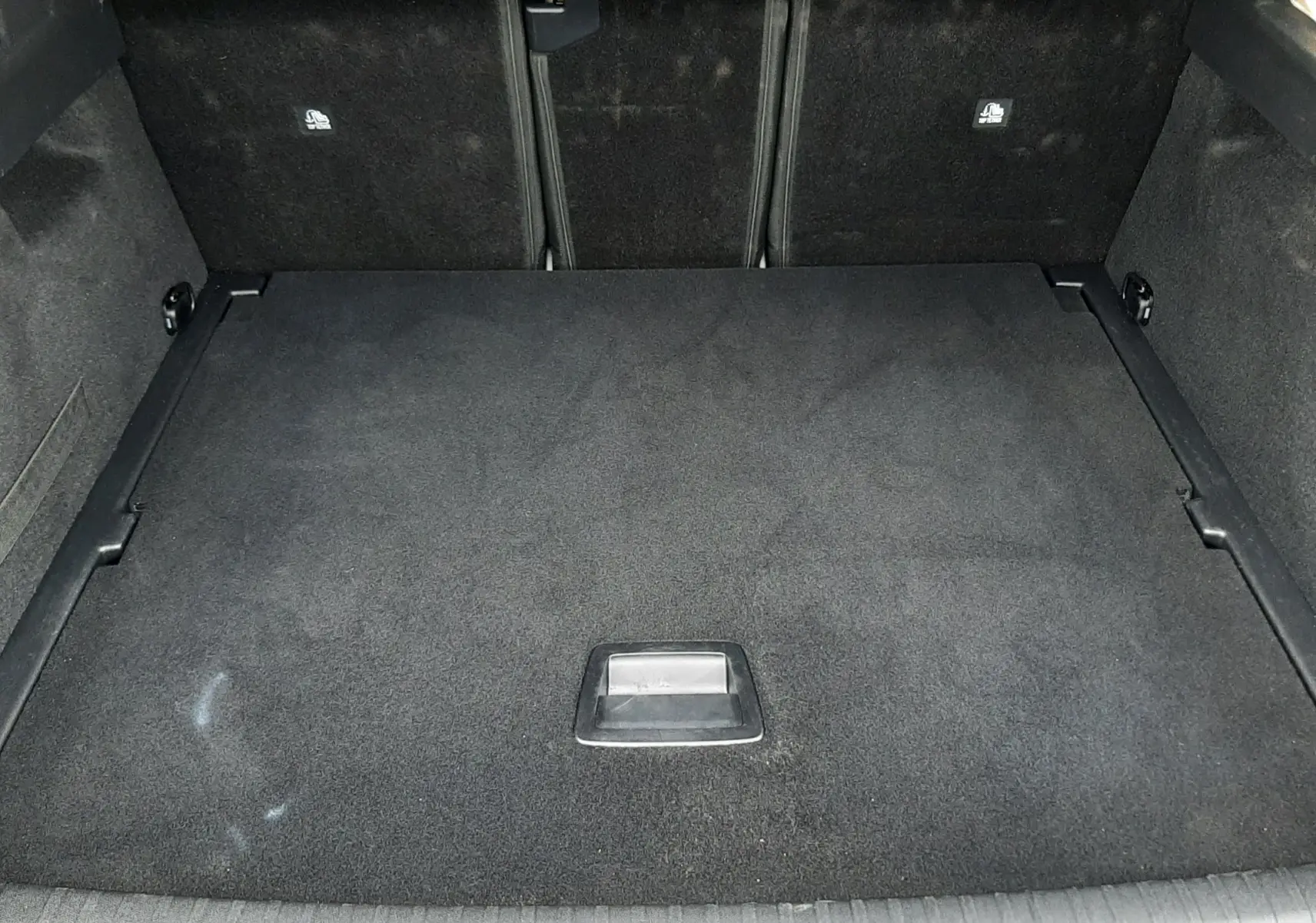 Vue intérieure du coffre fermé du Peugeot 3008 III Hybrid 145 Allure, revêtement noir et espace de rangement plat.