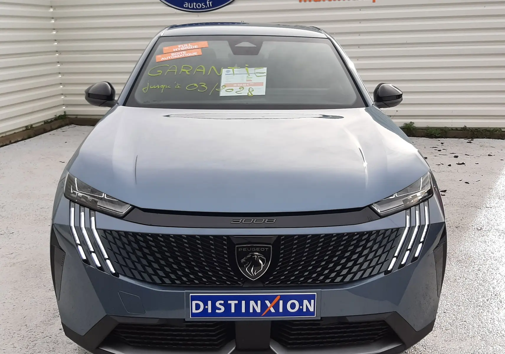 Vue frontale du Peugeot 3008 III HYBRID 145 Allure en bleu Ingaro, avec sa calandre distinctive et ses feux LED en forme de griffes.