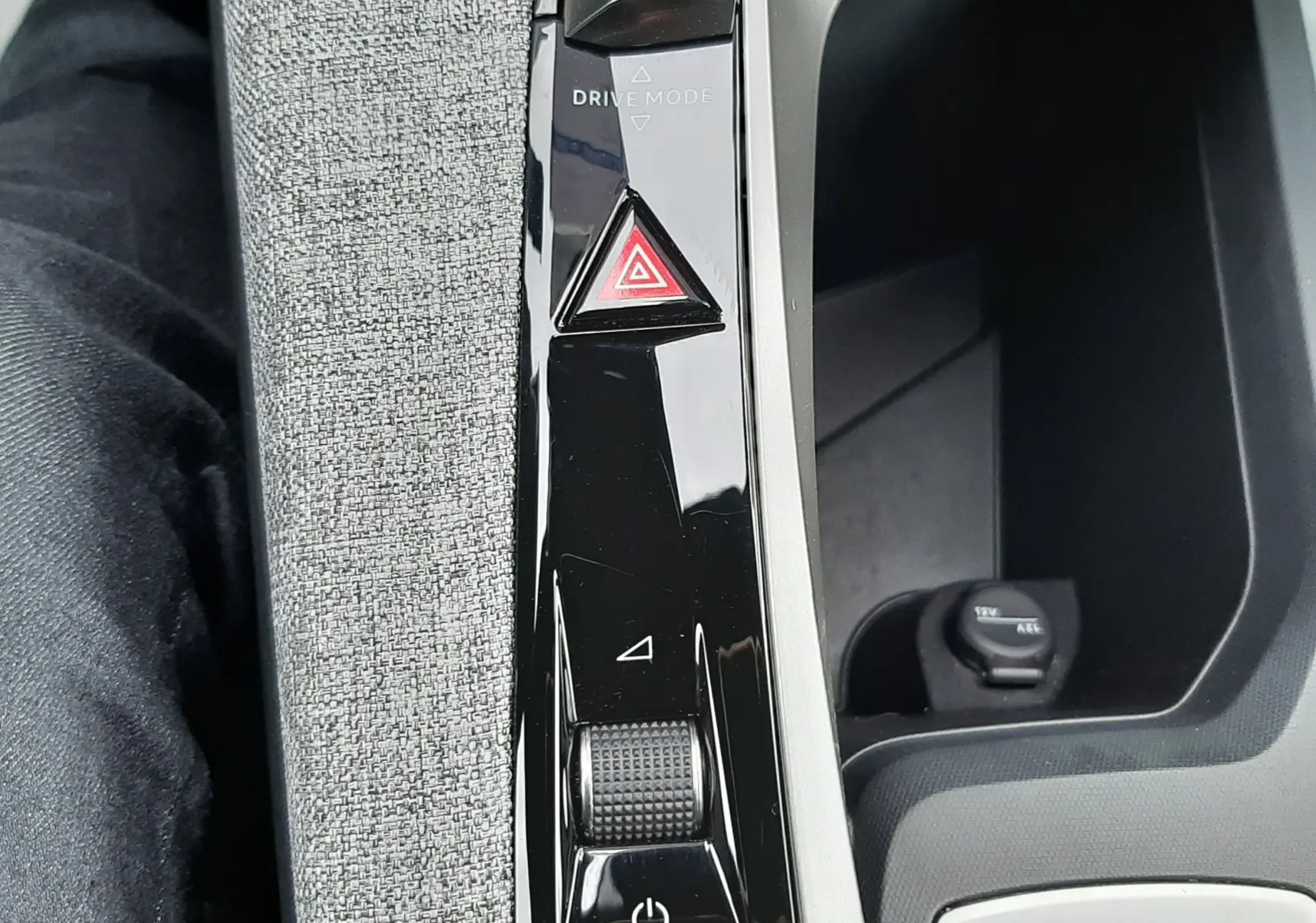 Gros plan sur la console centrale noire brillante du Peugeot 3008 bleu Ingaro, avec bouton de mode de conduite et alerte.
