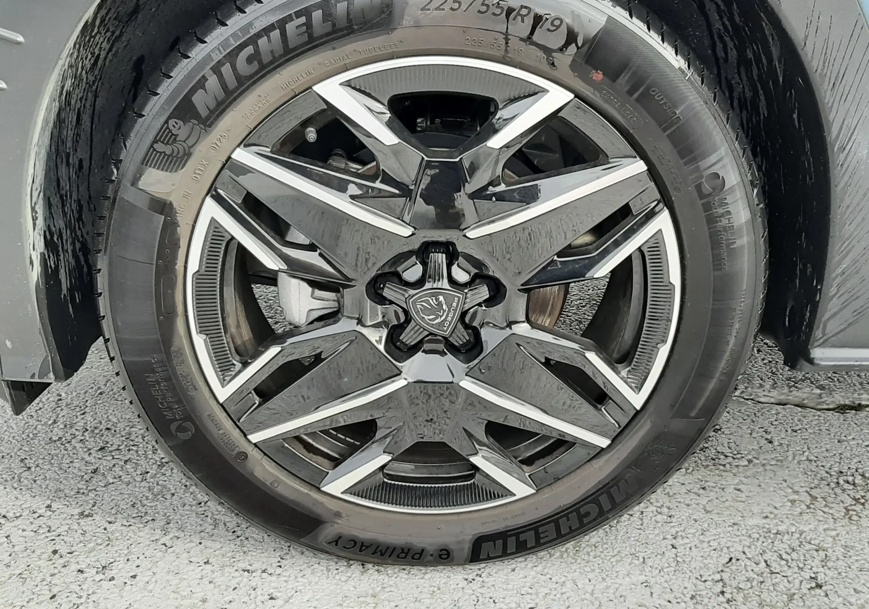 Gros plan sur la roue avant droite du Peugeot 3008 Bleu Ingaro, jante alliage noire et argentée avec logo Peugeot central.