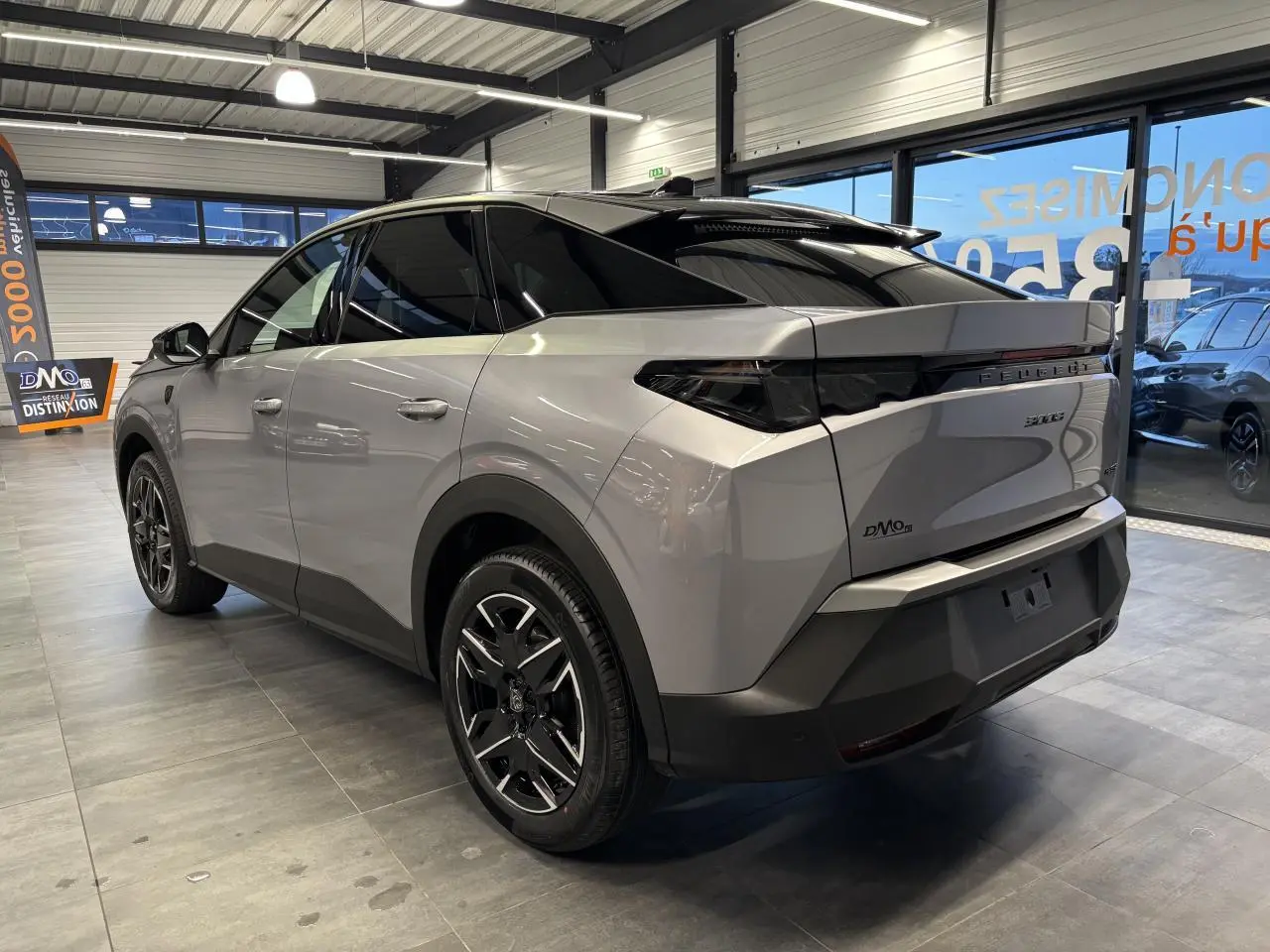 Vue 3/4 arrière droite d’un Peugeot 3008 gris Artense avec toit noir et jantes alliage 19 pouces en showroom.
