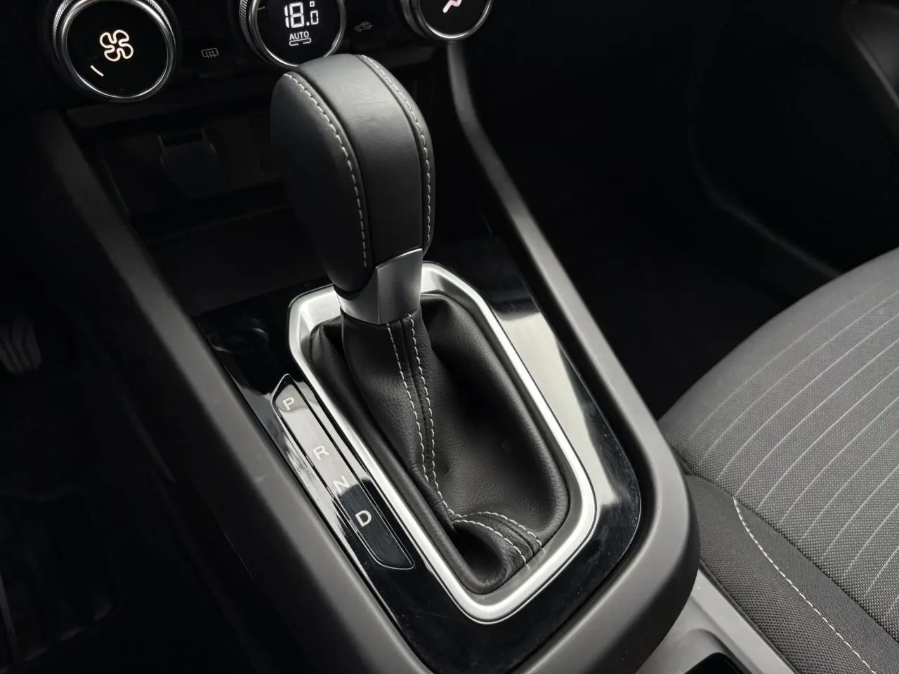 Gros plan sur le levier de vitesse automatique noir et coutures blanches de la Renault Arkana TCE 140 Evolution.