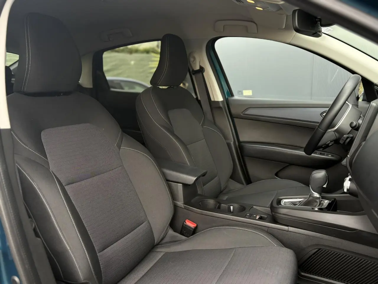 Vue intérieure côté droit du Renault Arkana 2025, sièges tissu noir avec accoudoir central et levier de vitesse automatique.