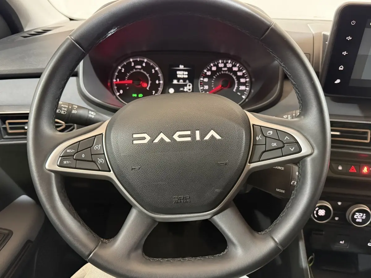 Vue rapprochée du volant en cuir synthétique noir de la Dacia Sandero 2024 avec commandes multifonctions visibles.