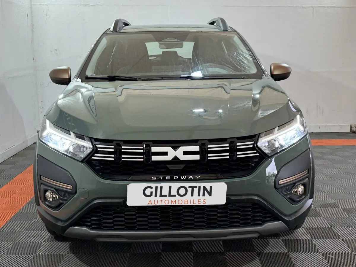 Vue frontale d'une Dacia Sandero Extreme+ TCe 110 2024 vert avec calandre noire et phares LED allumés.