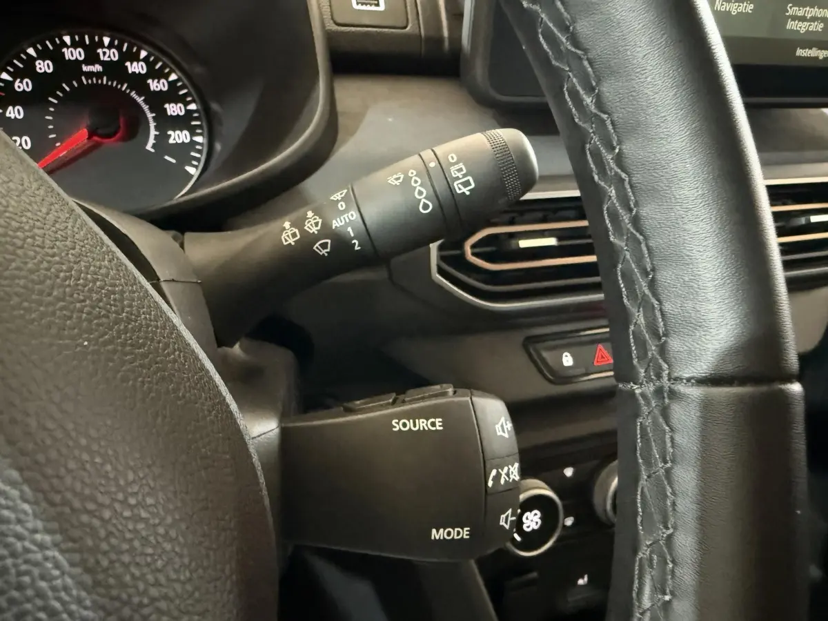 Gros plan sur le volant cuir synthétique et les commandes multifonctions du tableau de bord d'une Dacia Sandero Extreme+ verte 2024.