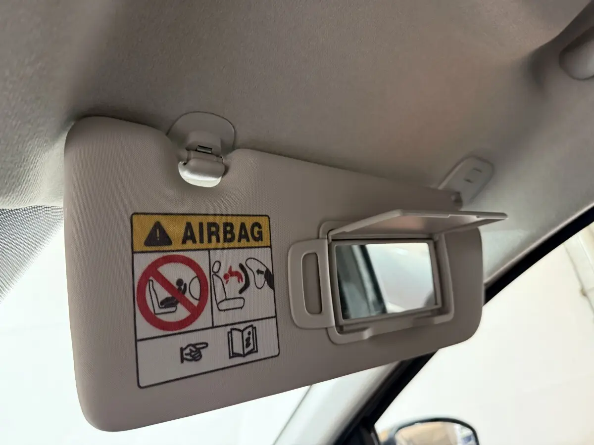Détail du pare-soleil côté conducteur avec miroir et avertissement airbag dans un Dacia Sandero vert 2024.