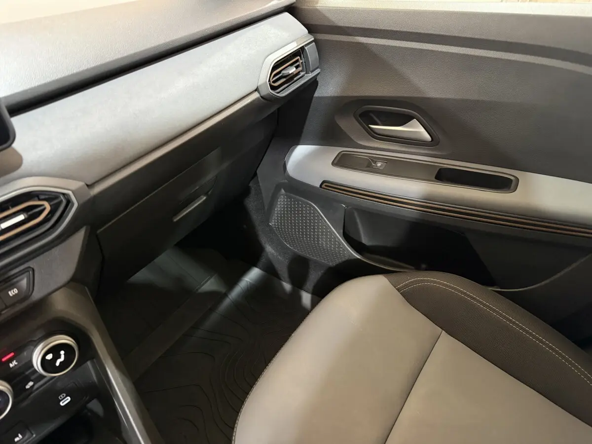 Vue intérieure côté passager avant de la Dacia Sandero Extreme+ 2024, avec siège gris et tableau de bord noir et gris.
