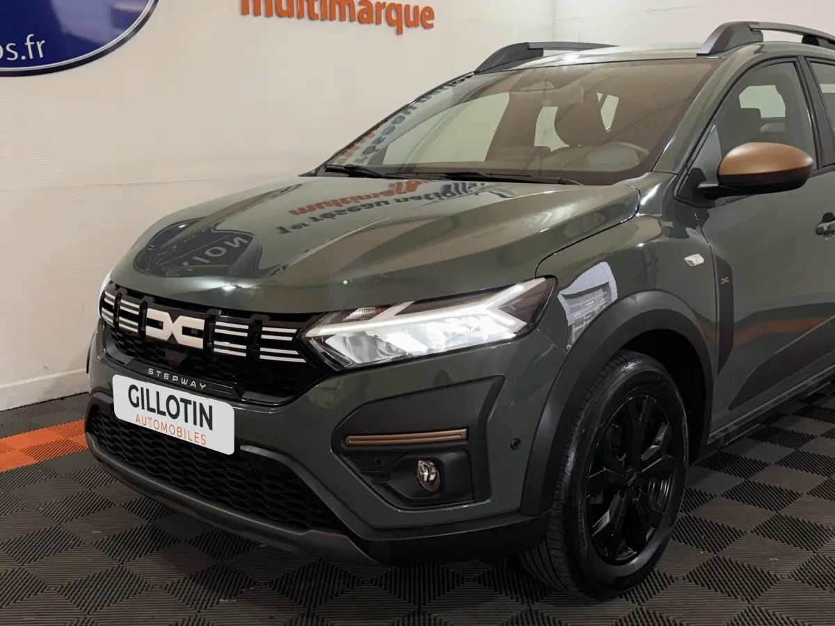 Vue 3/4 avant droite d'une Dacia Sandero Extreme+ TCe 110 2024 vert avec rétroviseurs bronze et jantes noires.