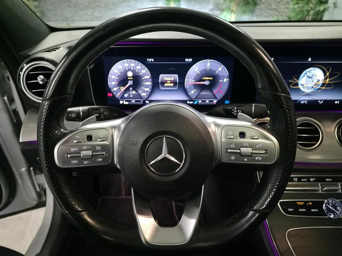 Vue rapprochée du volant en cuir noir et du tableau de bord numérique éclairé d’une Mercedes Classe E Break AMG Line 2020.