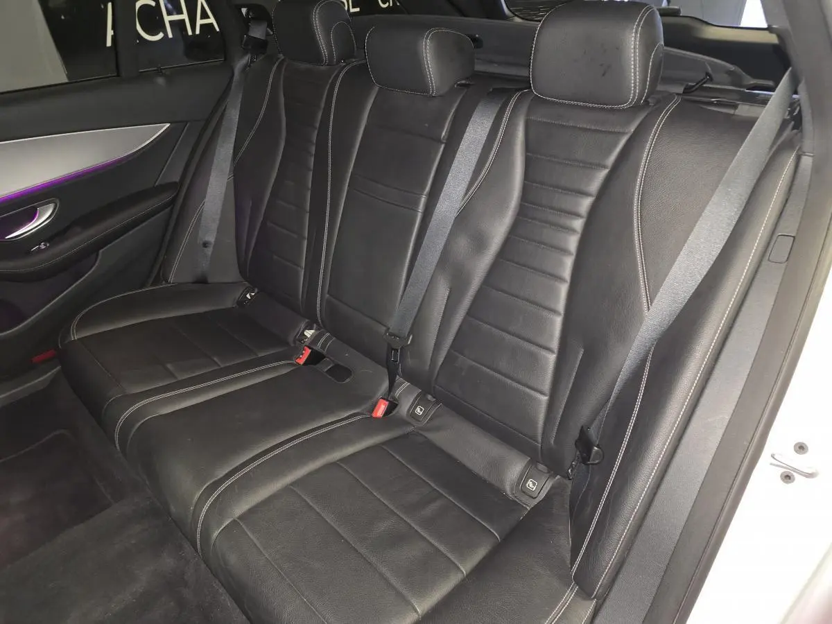 Vue côté droit de la banquette arrière en cuir noir avec surpiqûres blanches et éclairage d’ambiance violet d’une Mercedes Classe E Break 2020.