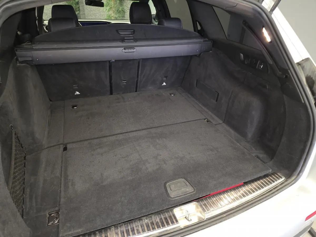 Coffre ouvert d'un break Mercedes Classe E gris, vue arrière montrant l'espace de chargement et la banquette rabattue.