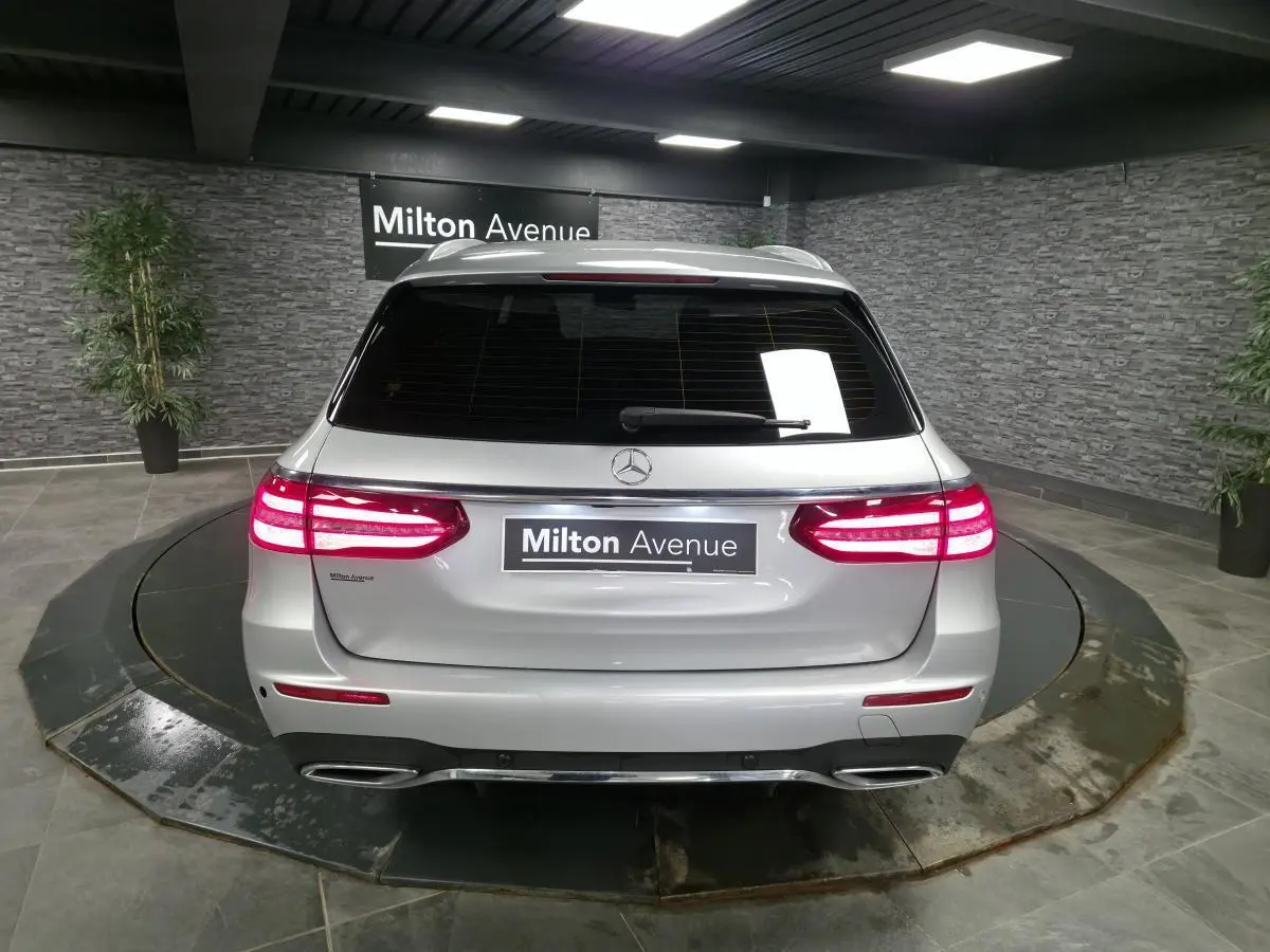 Vue arrière d'un break Mercedes Classe E gris métallisé avec feux LED allumés dans un showroom.