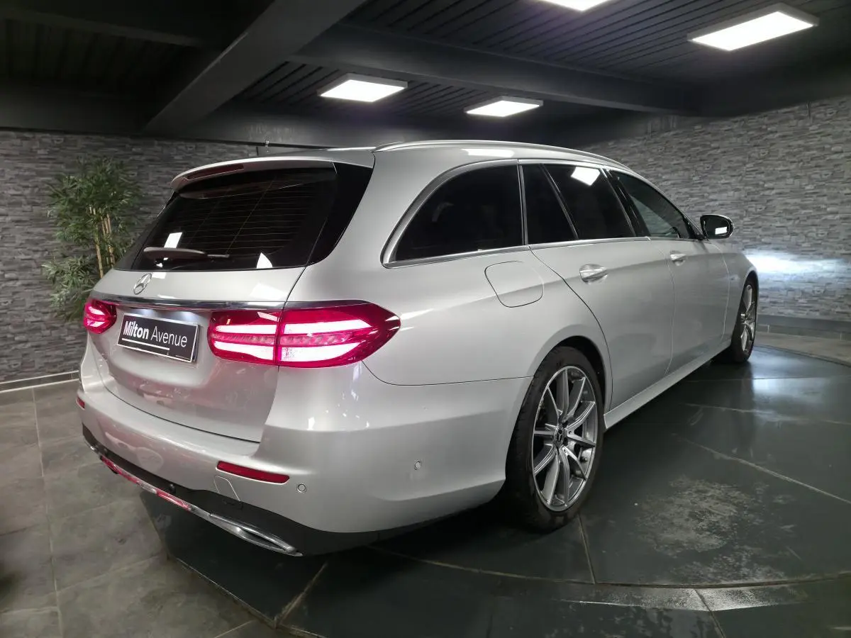 Vue 3/4 arrière droite d’un break Mercedes Classe E gris métallisé avec jantes AMG 19 pouces et vitres teintées.