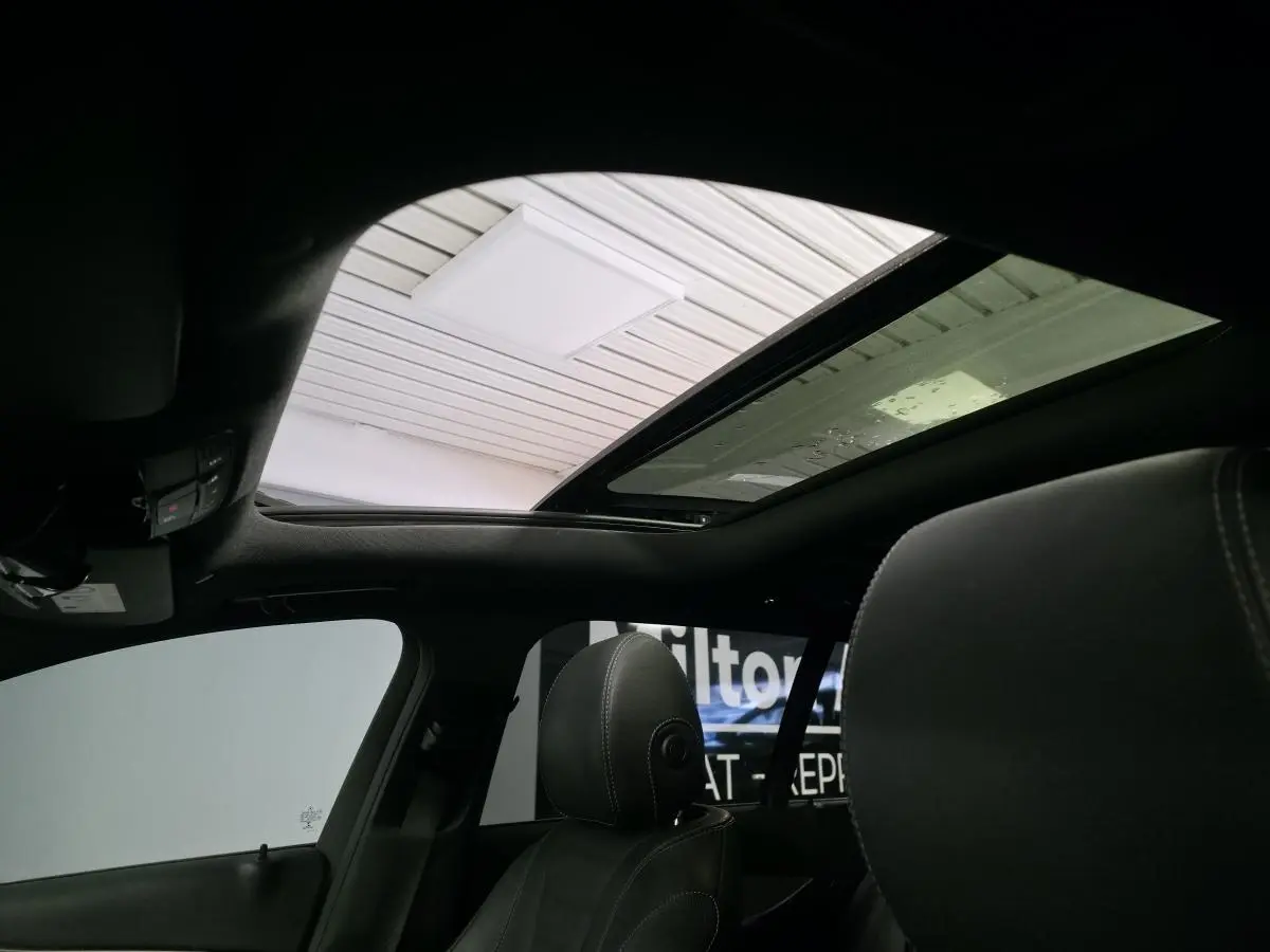 Vue intérieure du toit ouvrant panoramique en verre d'une Mercedes Classe E Break gris, avec sièges avant en cuir noir.