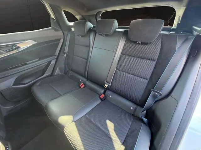 Vue intérieure arrière montrant la banquette noire du Renault Austral Esprit Alpine hybride 2025 avec ceintures et appuie-têtes.