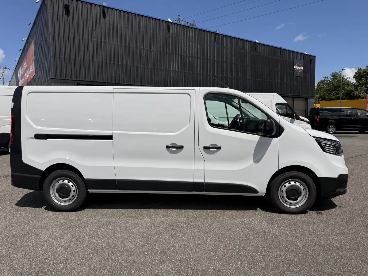 Renault Trafic Fourgon blanc vu de profil côté gauche, avec porte latérale coulissante et jantes acier.