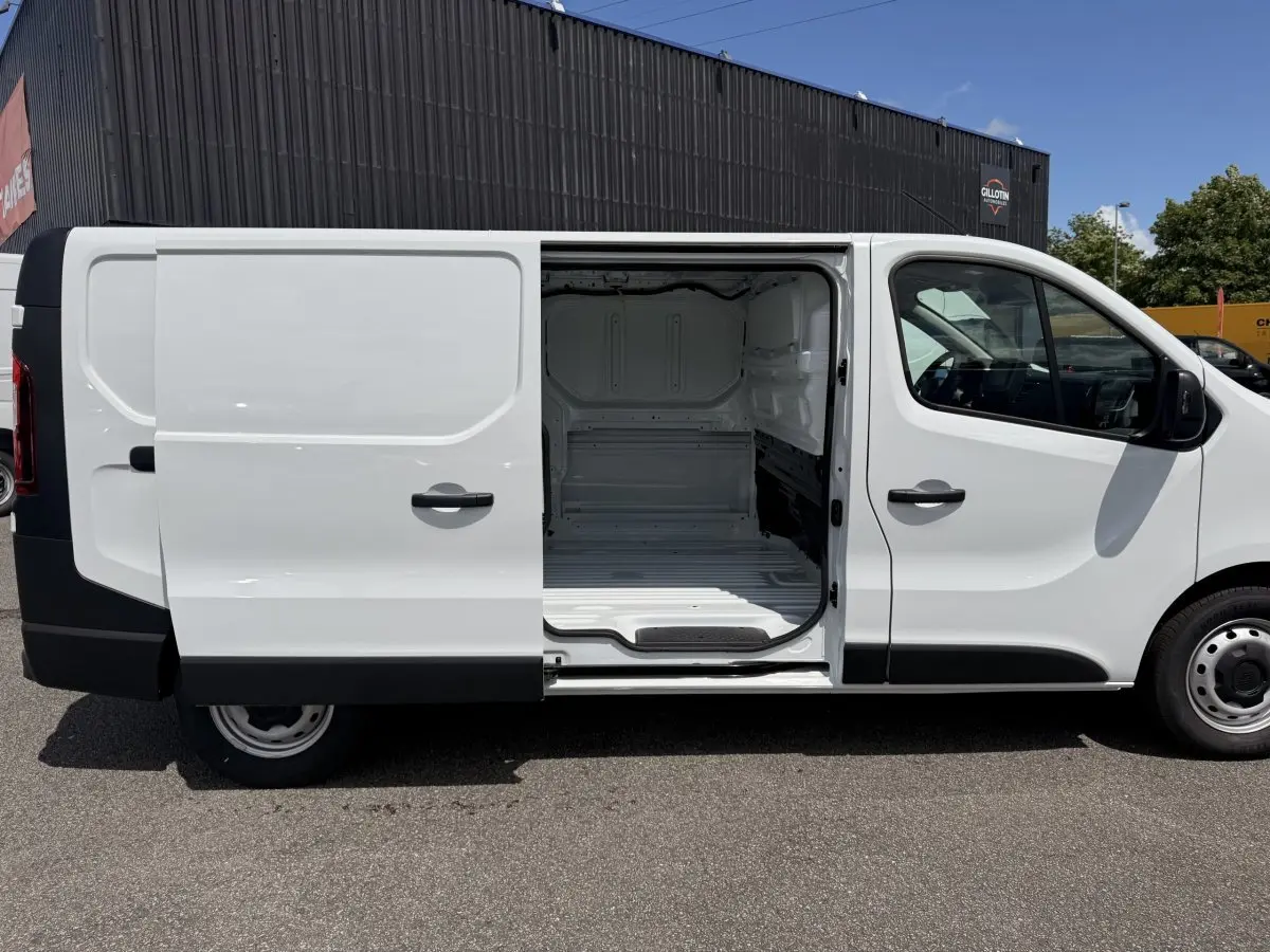 Vue latérale droite d’un Renault Trafic Fourgon blanc 2025 avec porte coulissante ouverte montrant l’espace de chargement vide.
