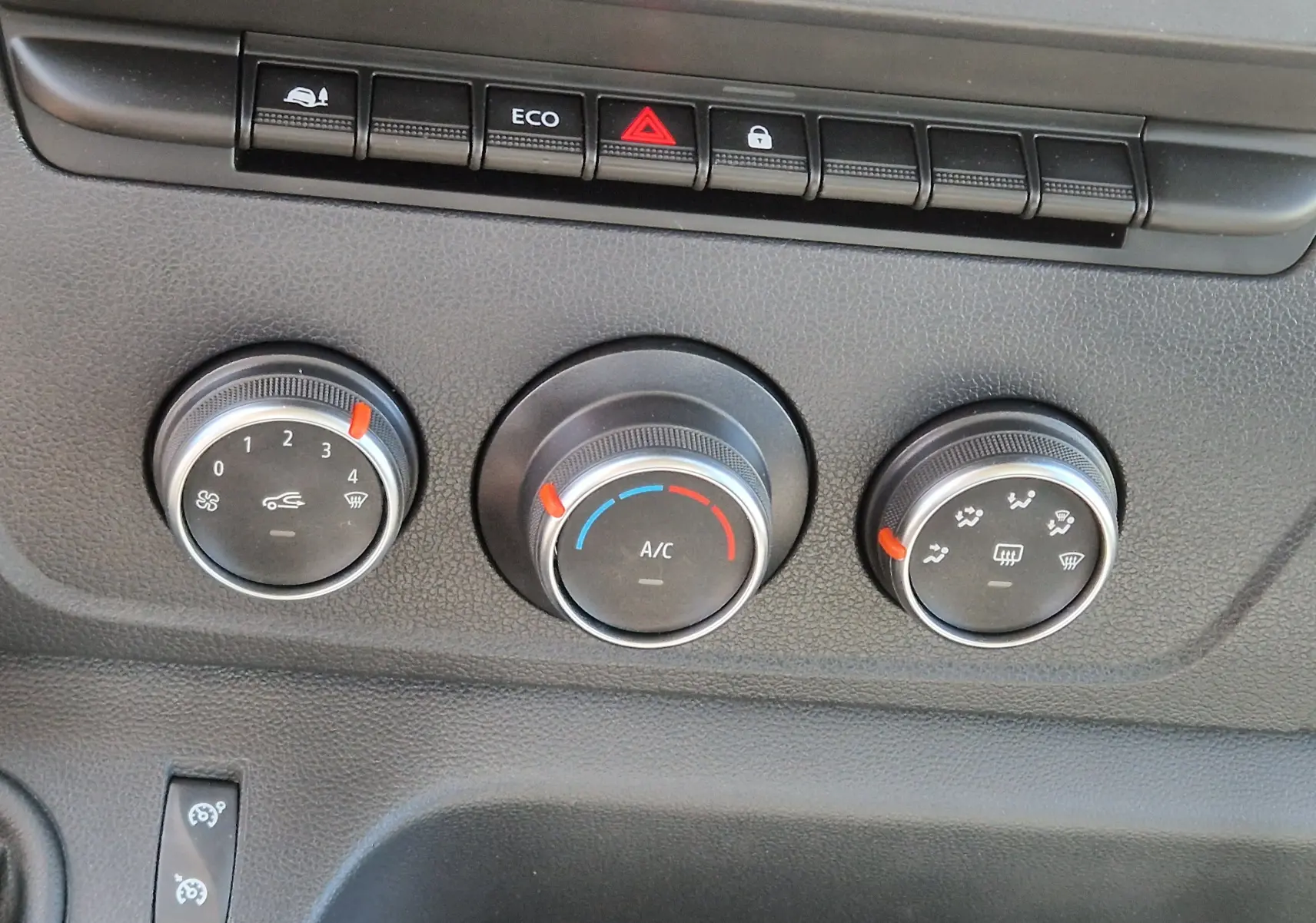 Gros plan sur les commandes de climatisation et les boutons de fonction du tableau de bord du Renault Master Châssis Cabine blanc.