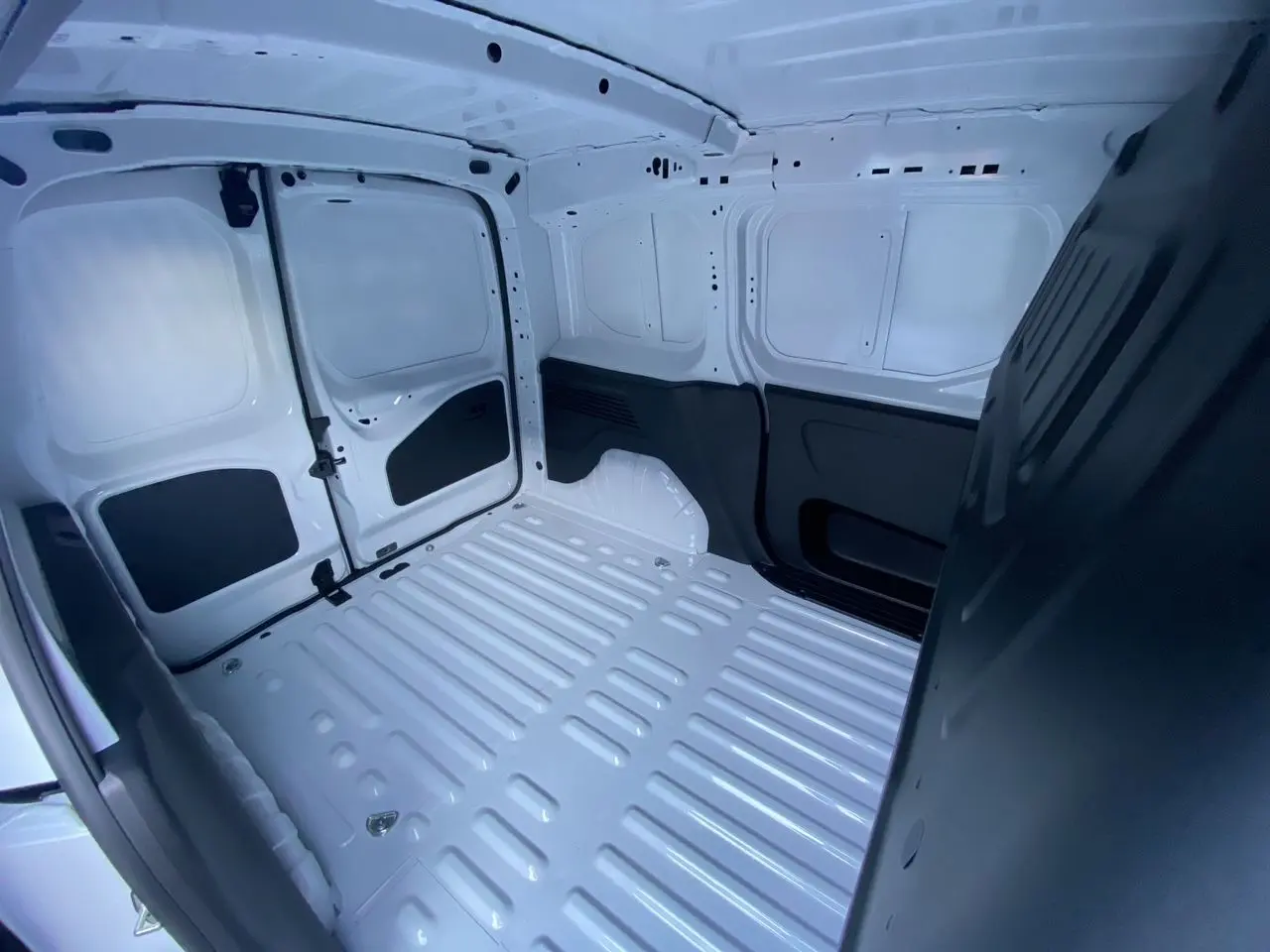 Intérieur du coffre blanc du Peugeot Partner 2024, vue plongeante montrant l’espace de chargement vide et les parois métalliques.
