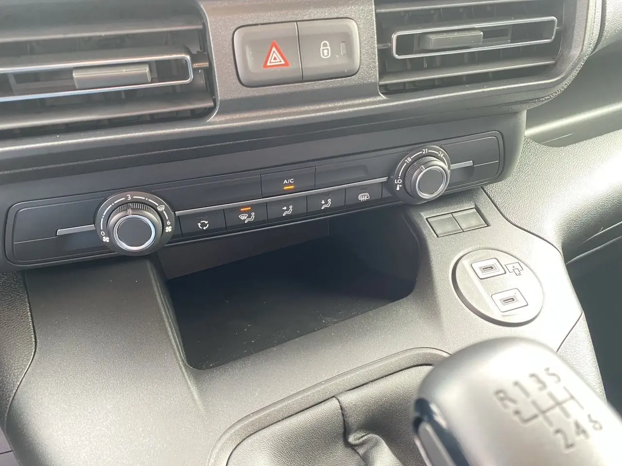 Vue rapprochée de la console centrale du Peugeot Partner blanc 2024, avec commandes climatisation et levier de vitesse manuel.