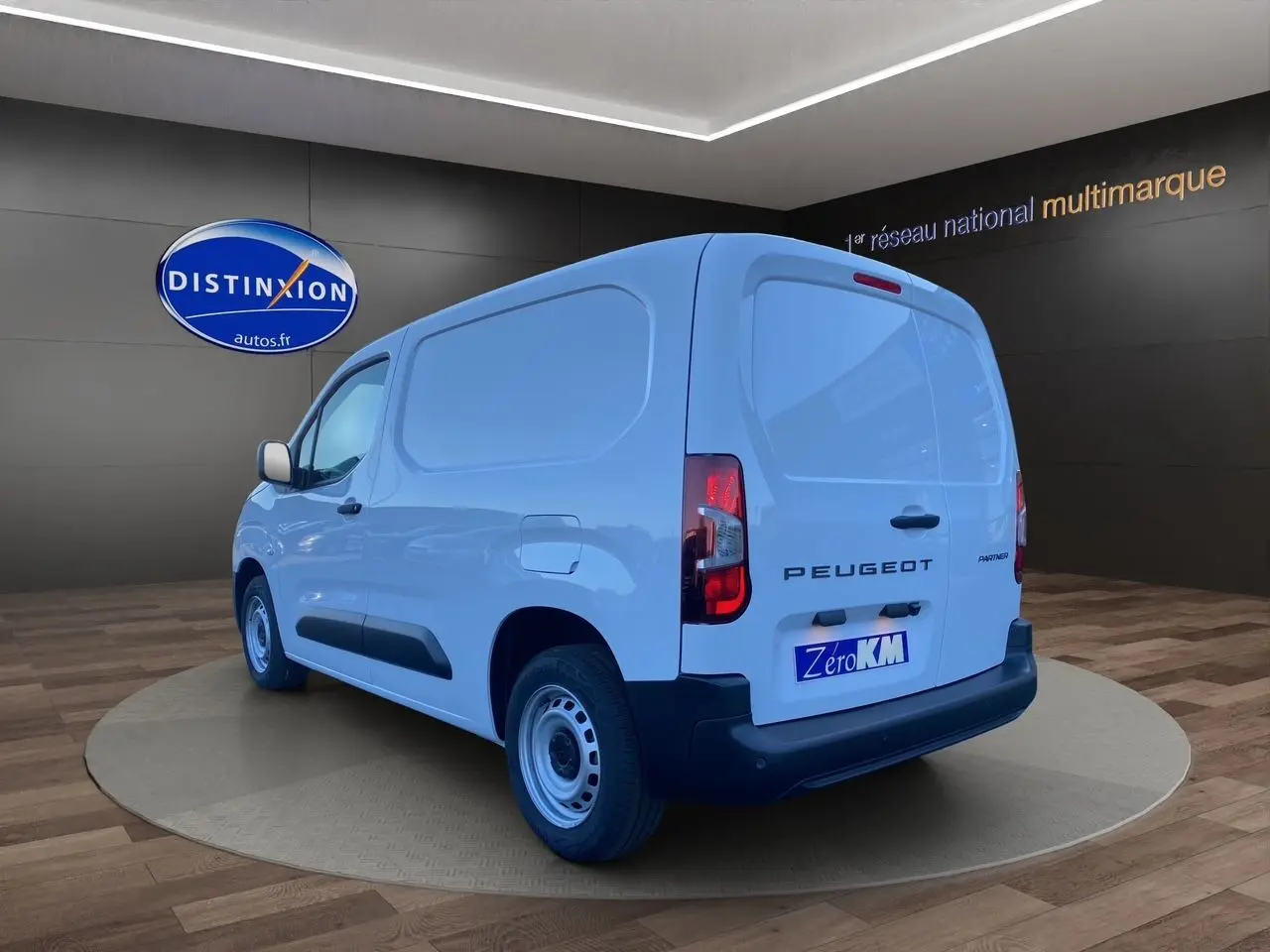 Vue 3/4 arrière droite du Peugeot Partner blanc, fourgon utilitaire avec logo et feux arrière visibles.