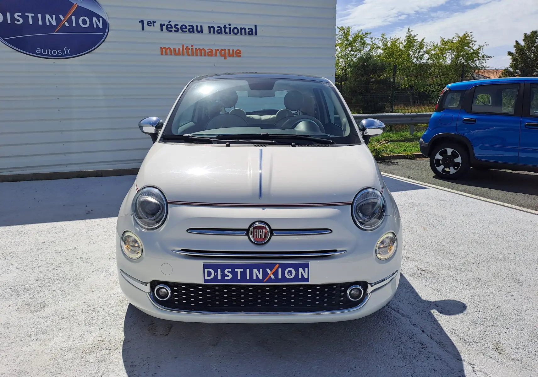 Vue frontale d'une FIAT 500 blanche 1.0 Hybrid 70CH DolceVita avec calandre chromée et logo rouge visible.