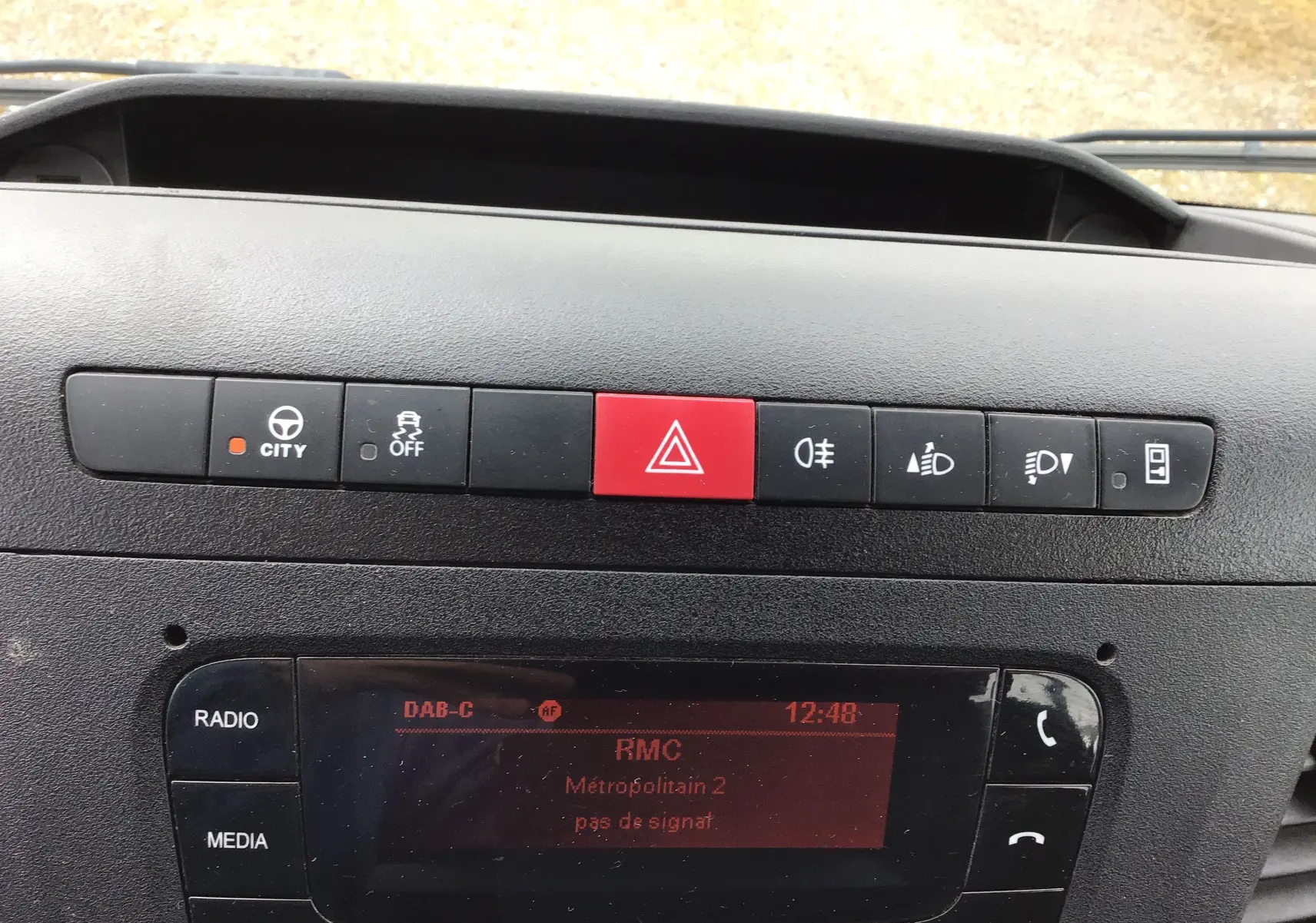 Gros plan sur la console centrale noire de l’Iveco Daily 2021, montrant les boutons de commande et l’écran radio allumé.