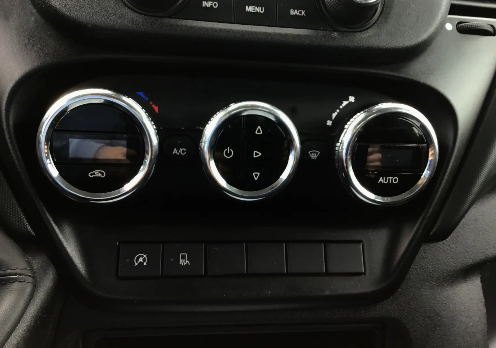 Gros plan sur les commandes de climatisation automatique du tableau de bord noir de l'Iveco Daily Chassis double cabine blanc.