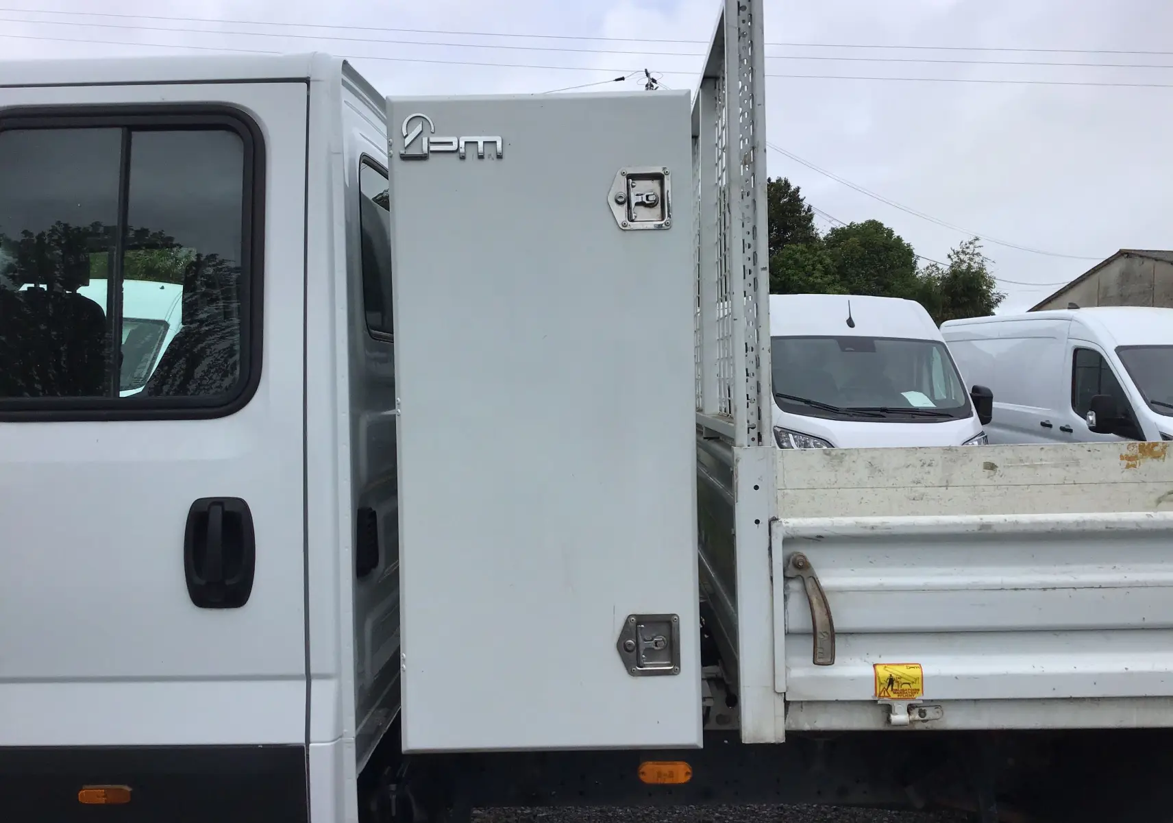 Vue latérale droite du camion blanc Iveco Daily Chassis double cabine avec benne et coffre latéral fermé.