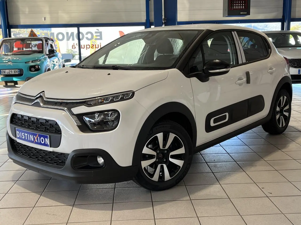 Citroën C3 blanche vue 3/4 avant droit, avec Airbump noir et jantes alliage diamantées en showroom.
