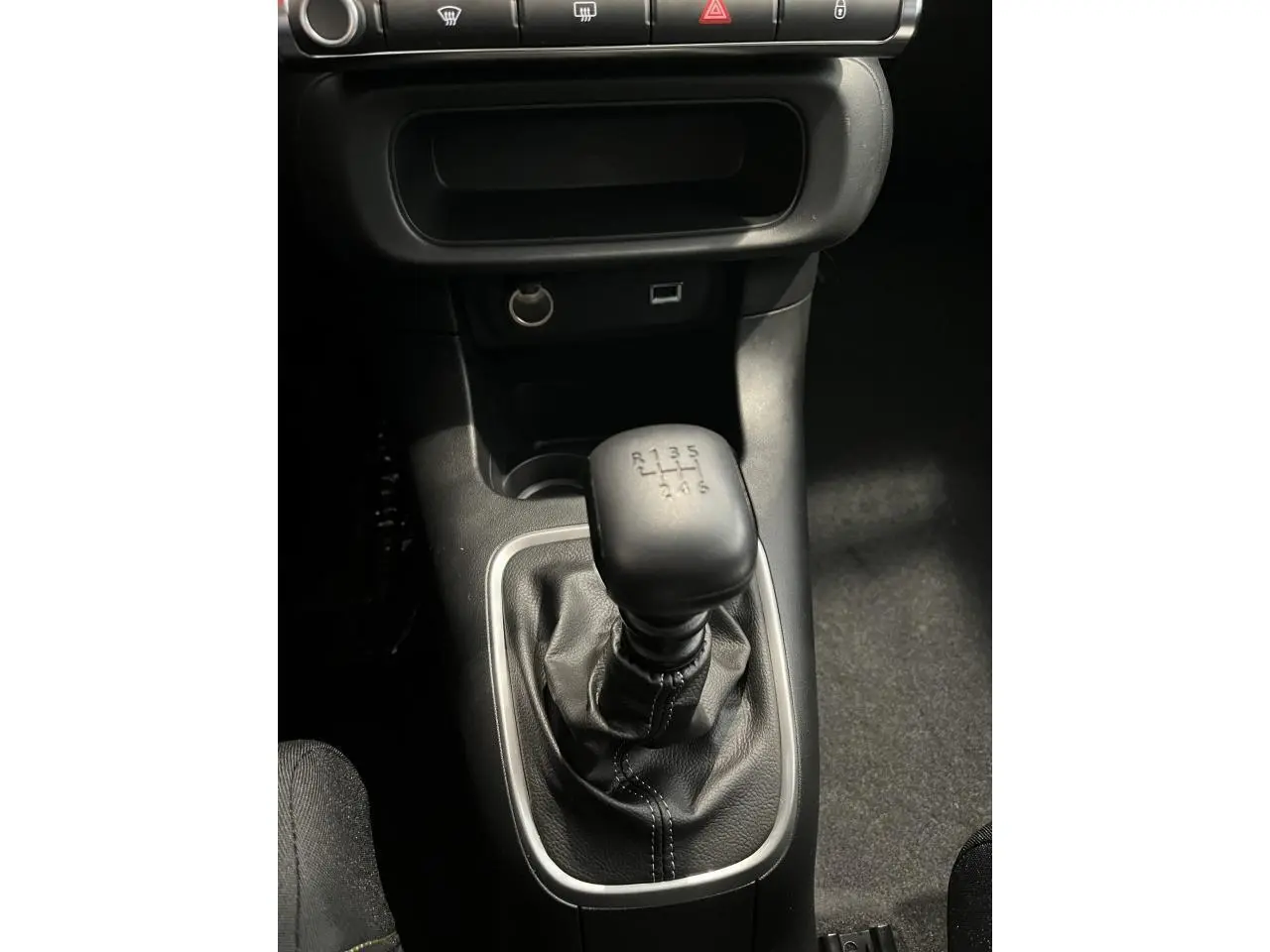 Le levier de vitesse manuel noir de la Citroën C3 2024 vu de dessus, entouré de garniture grise.