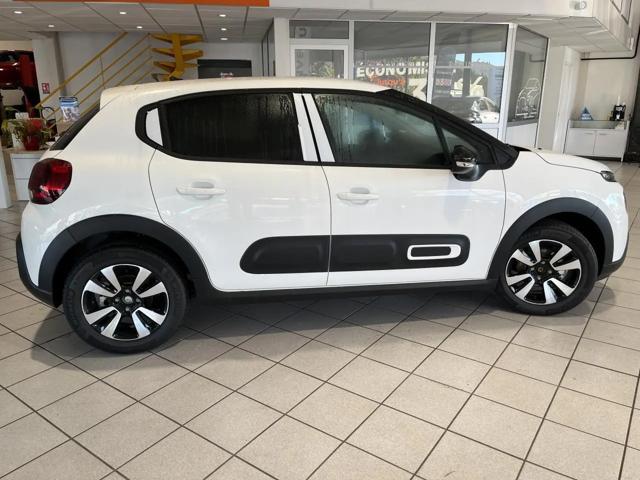 Profil droit d'une Citroën C3 blanche avec Airbump noir et jantes alliage diamantées en showroom.