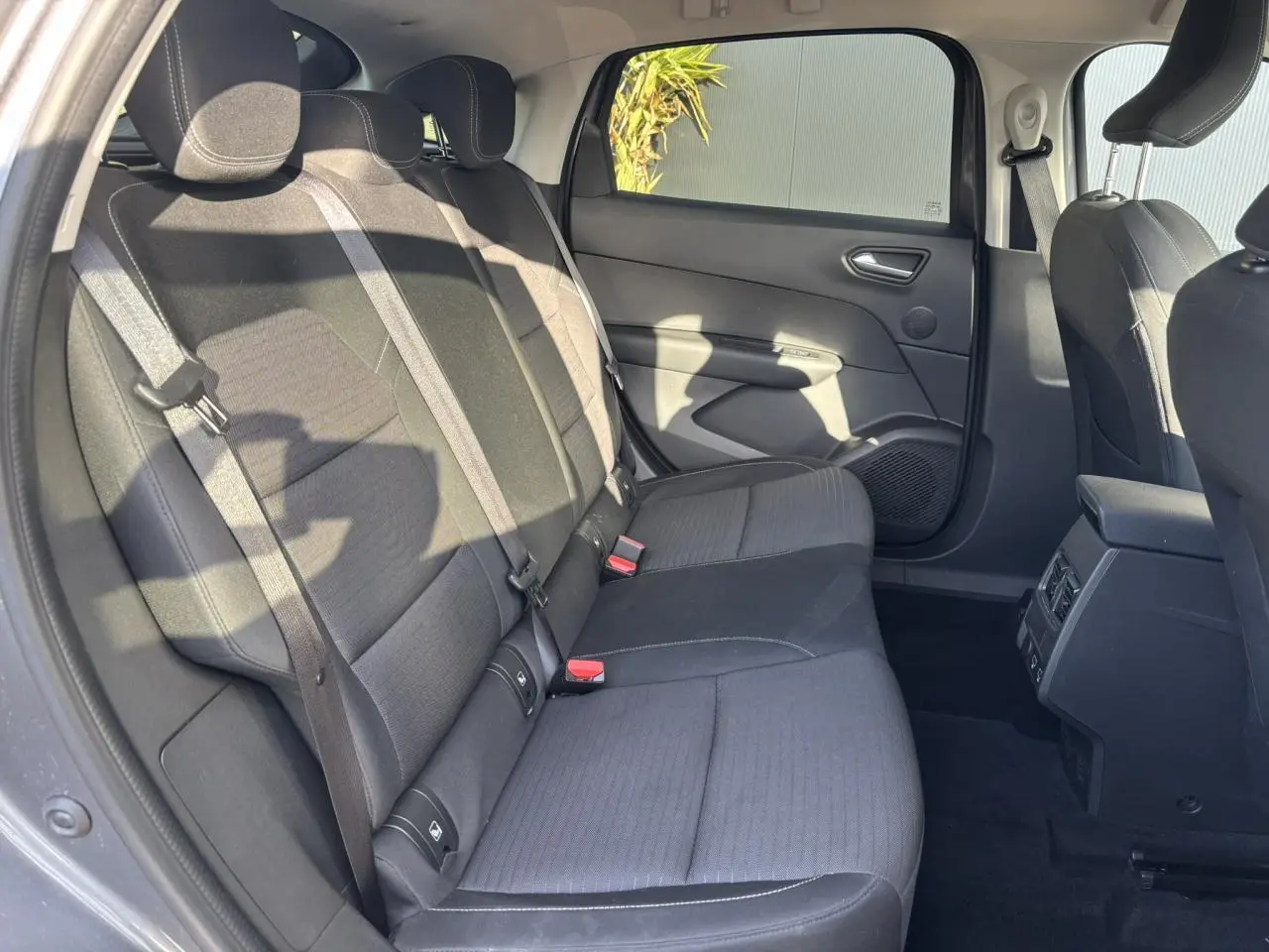Vue intérieure côté gauche sur la banquette arrière tissu noir avec vitres latérales surteintées d’un Renault Arkana gris métallisé.