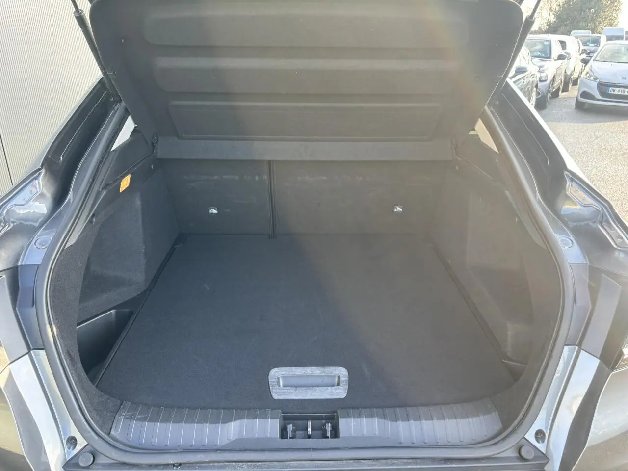 Coffre ouvert vu de l'arrière d'une Renault Arkana gris métallisé, montrant un espace de chargement vide et propre.