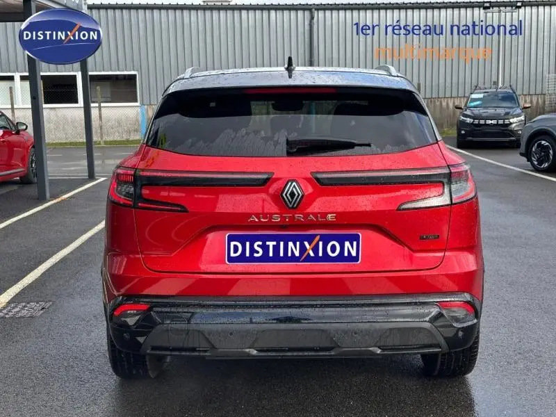 Vue arrière d'un Renault Austral Rouge Flamme 2025 avec logo et feux arrière fins, garé sur parking extérieur.