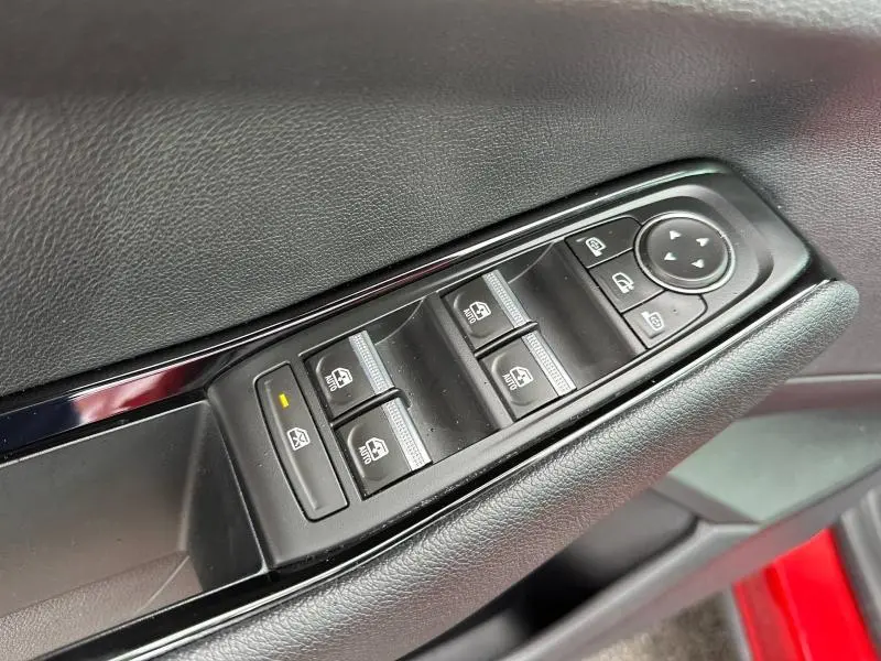 Gros plan sur les commandes des vitres électriques côté conducteur d’un Renault Austral Rouge Flamme 2025, finition Techno.