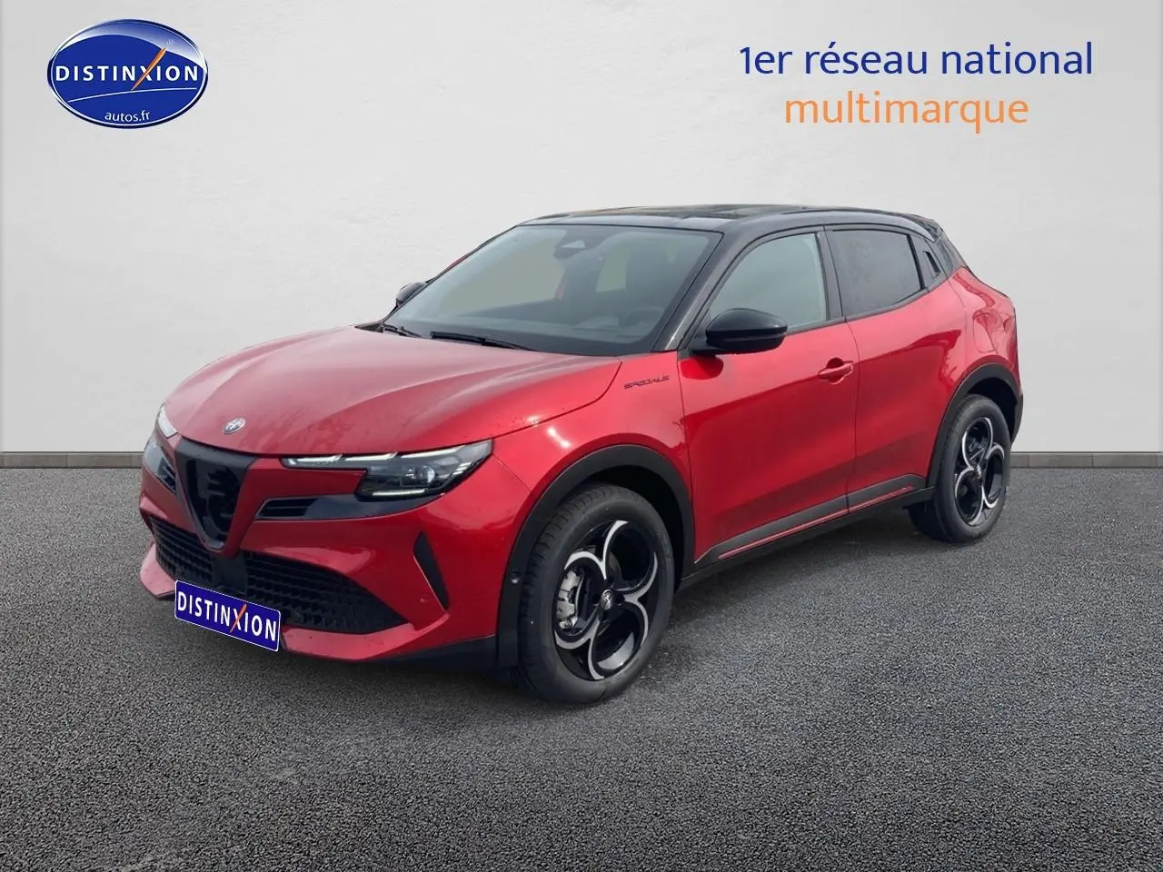 Alfa Romeo Junior 1.2 hybride 2026 rouge et noir, vue 3/4 avant avec jantes alliage et toit noir contrasté.