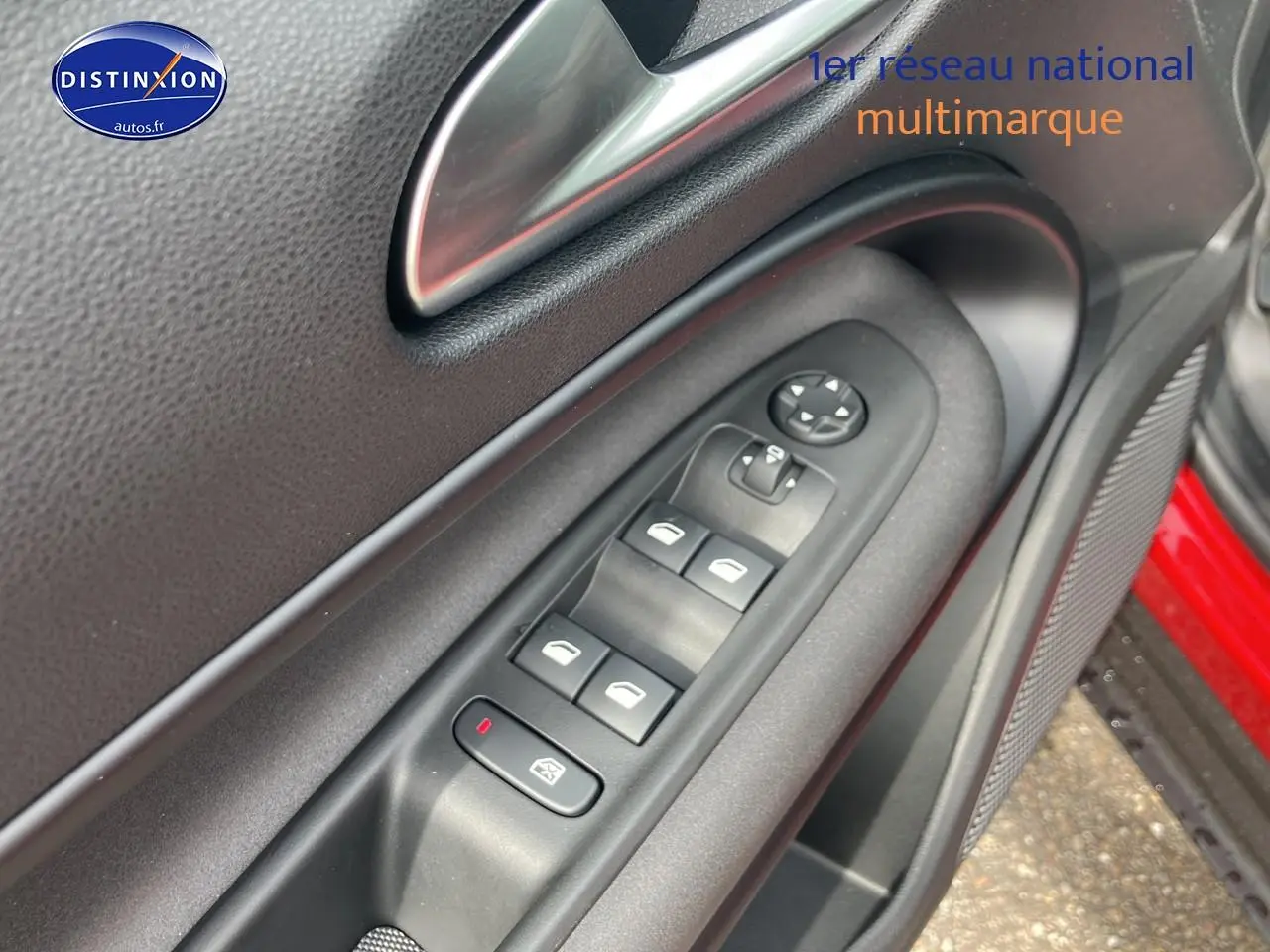 Gros plan sur la commande des vitres côté conducteur de l'Alfa Romeo Junior rouge, avec poignée intérieure et haut-parleur.