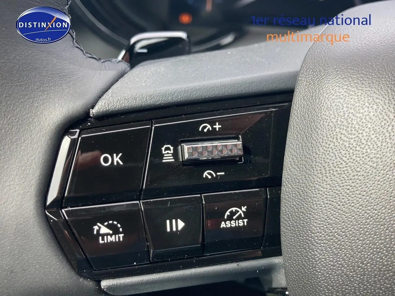 Gros plan sur les commandes au volant noir de l'Alfa Romeo Junior 1.2 hybride, avec boutons de régulateur et assistance.