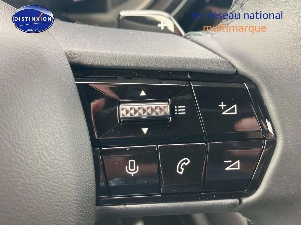 Gros plan sur les commandes au volant noir de l'Alfa Romeo Junior 1.2 hybride 2026, avec boutons de volume et appels.