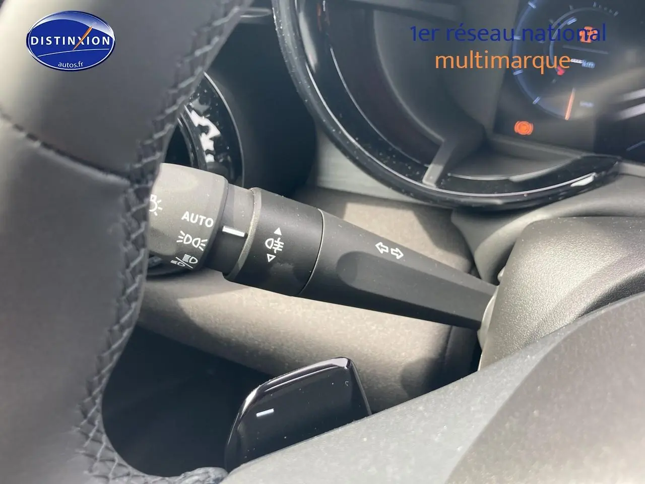 Détail du commodo d’éclairage et clignotants sur le côté gauche du volant d’une Alfa Romeo Junior 1.2 hybride rouge/noir.