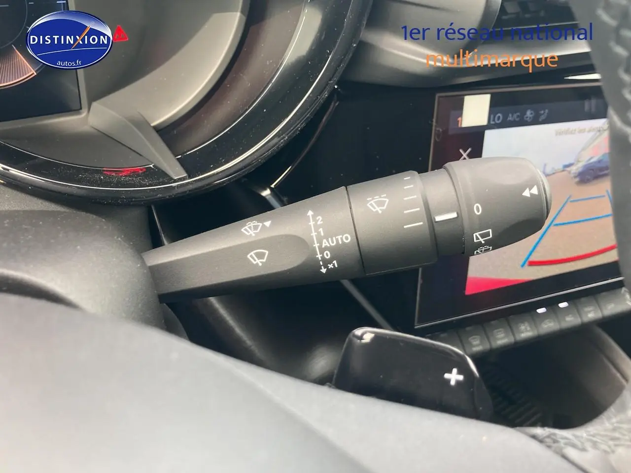 Détail du commodo d’essuie-glace dans l’habitacle d’une Alfa Romeo Junior 1.2 hybride rouge/noir, avec écran tactile et caméra de recul.