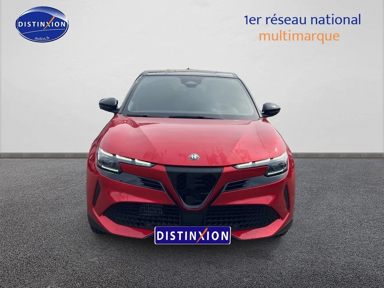 Vue frontale d'une Alfa Romeo Junior 1.2 hybride rouge et noir avec calandre noire et phares LED fins.