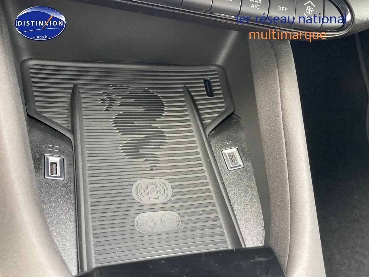 Gros plan sur le chargeur à induction noir avec logo serpent Alfa Romeo, entouré de ports USB dans l'habitacle.