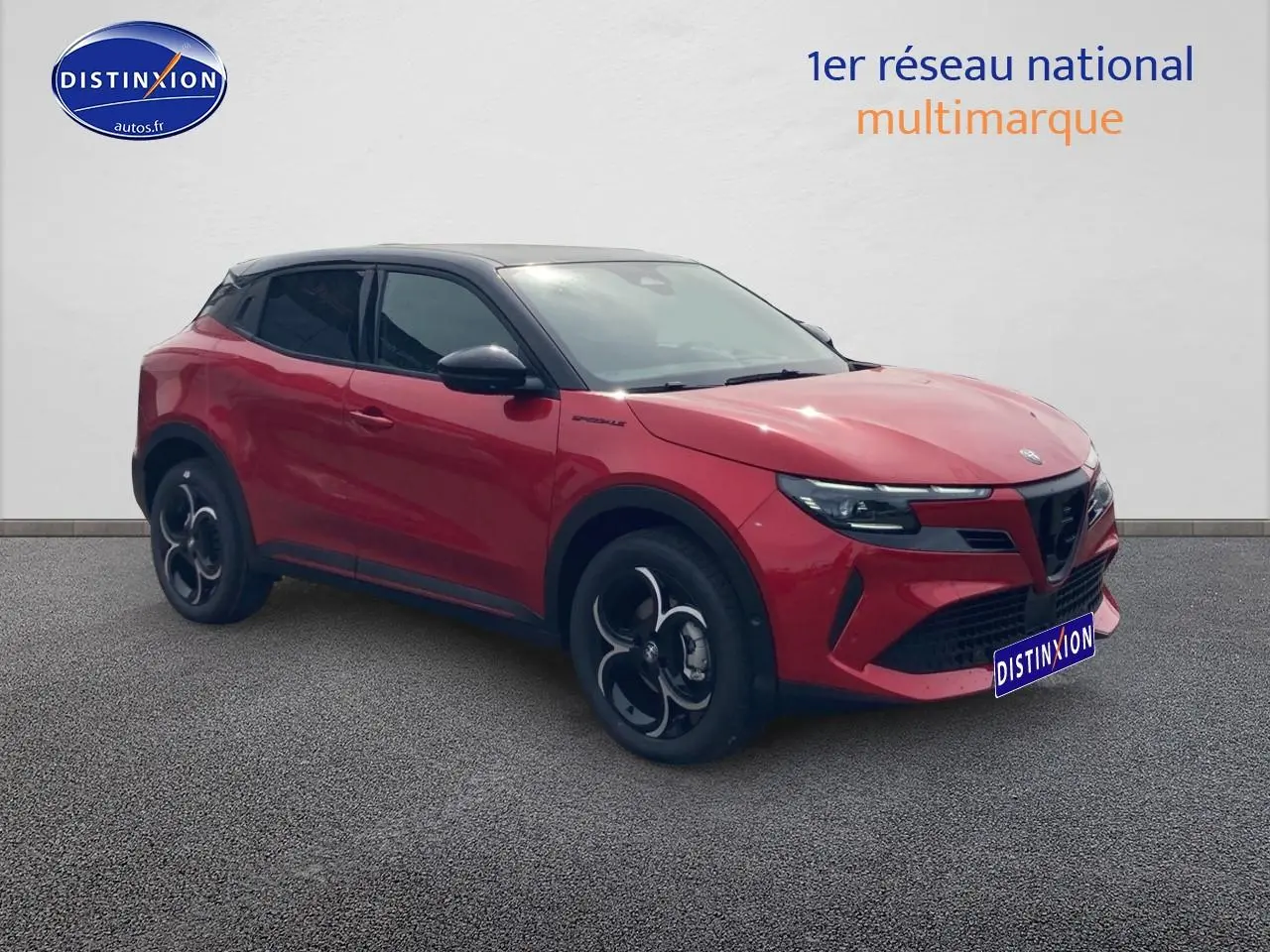 Vue 3/4 avant droite d'une Alfa Romeo Junior 1.2 hybride rouge et toit noir avec jantes alliage noires.