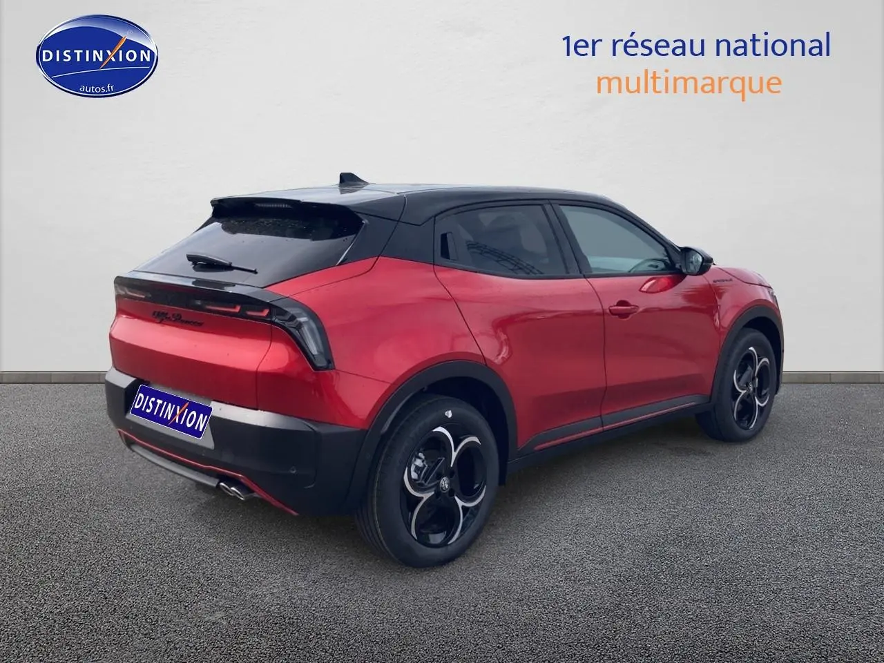 Vue 3/4 arrière droite d'une Alfa Romeo Junior 1.2 hybride rouge et noir avec jantes en alliage et toit noir.